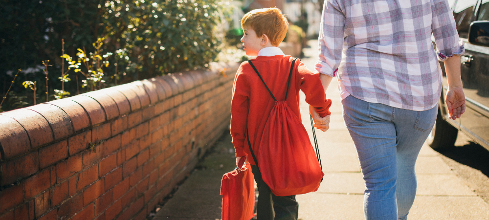 Young boy and his foster carer walk to school